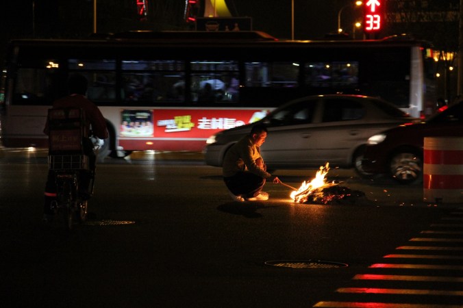 A man burns paper money in Tianjin