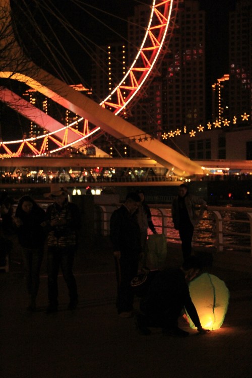 People light lanterns near the Tianjin Eye
